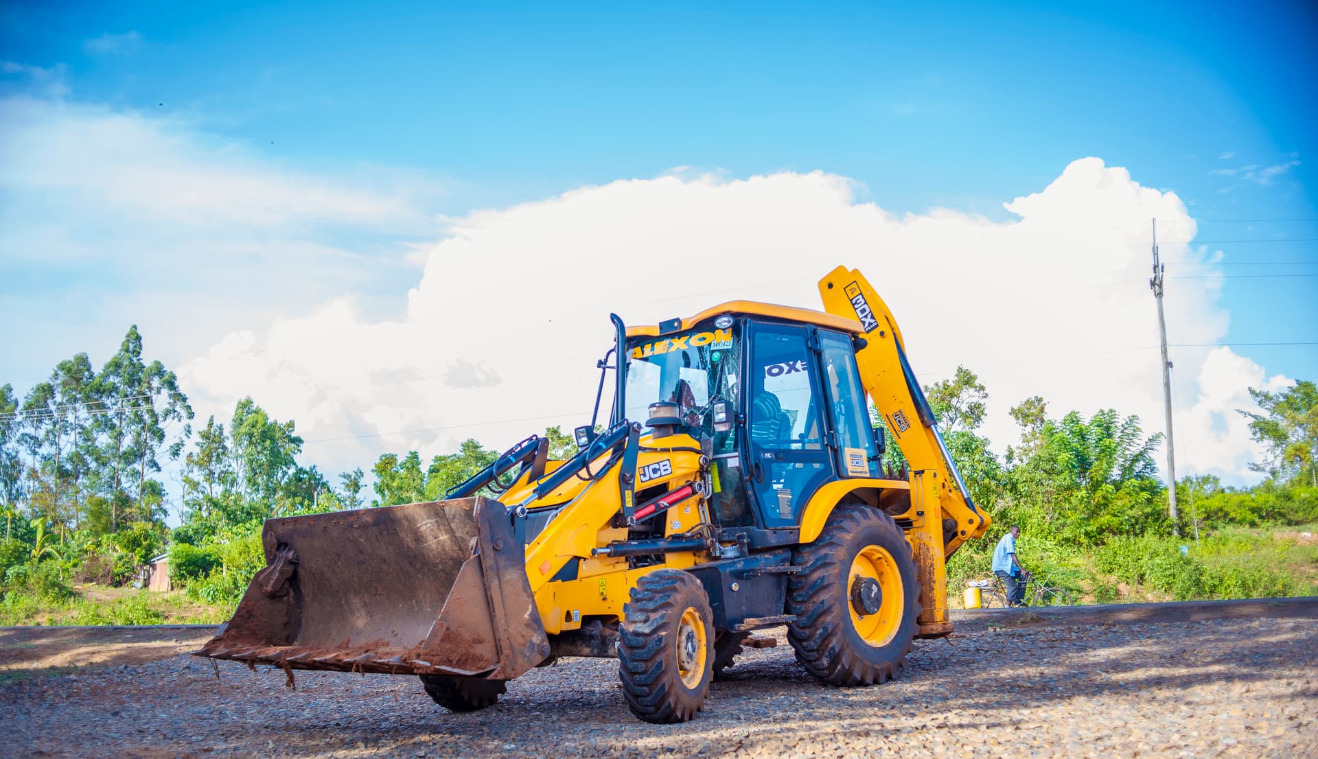 Alexon-liveried JCB backhoe loader on a murram site